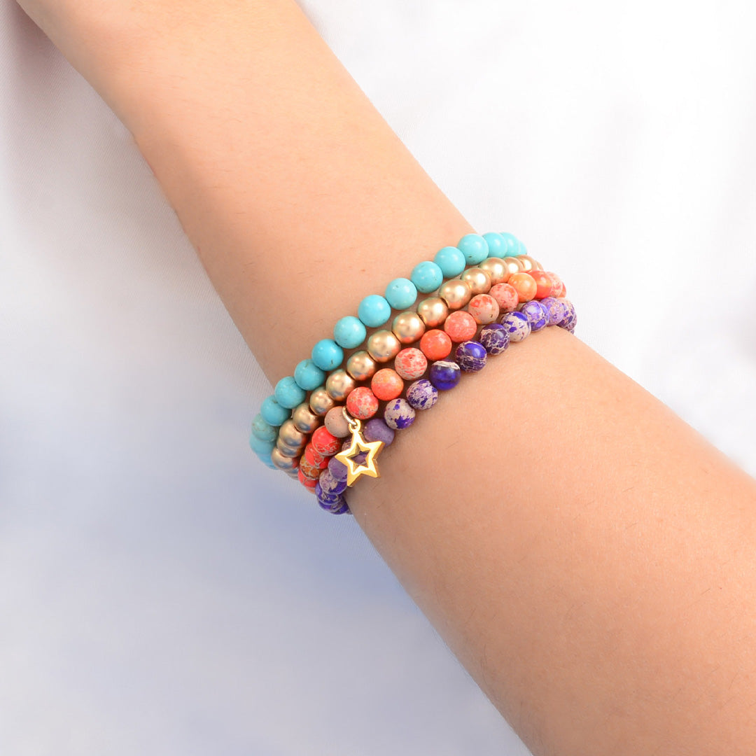 Multicolored beaded bracelet with a star charm on a wrist against a light background
