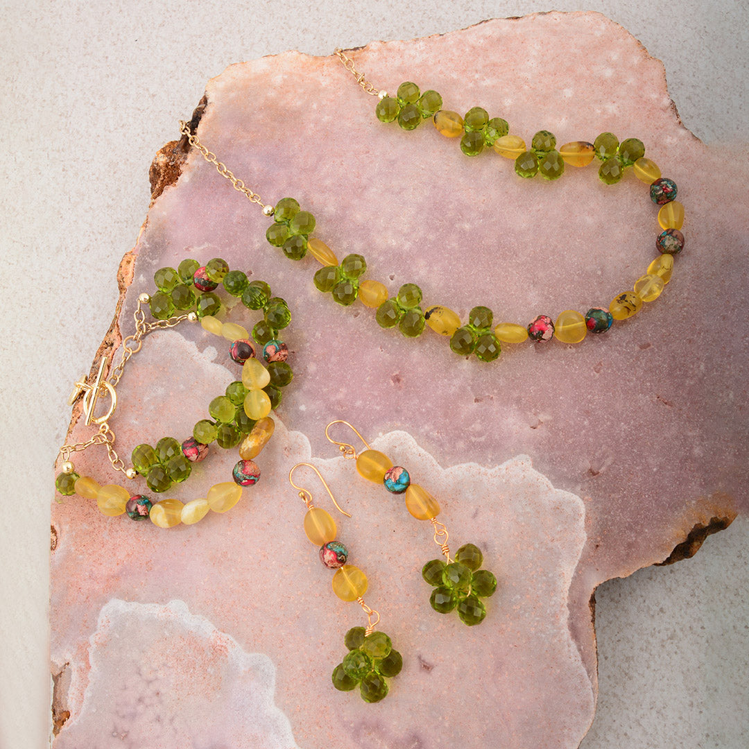 Beaded jewelry set with necklace and earrings on a pink stone surface