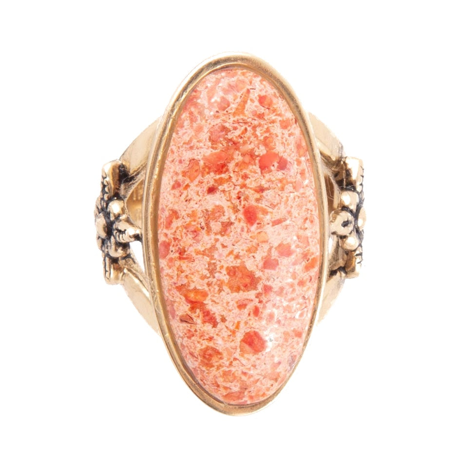 Ring with pink speckled stone and gold band on a white background