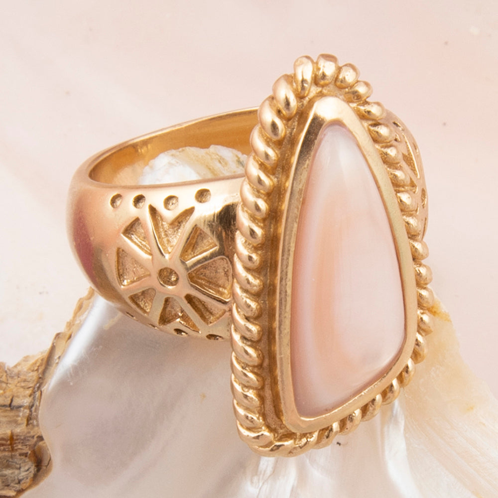 Gold ring with a teardrop-shaped pearl on a shell background