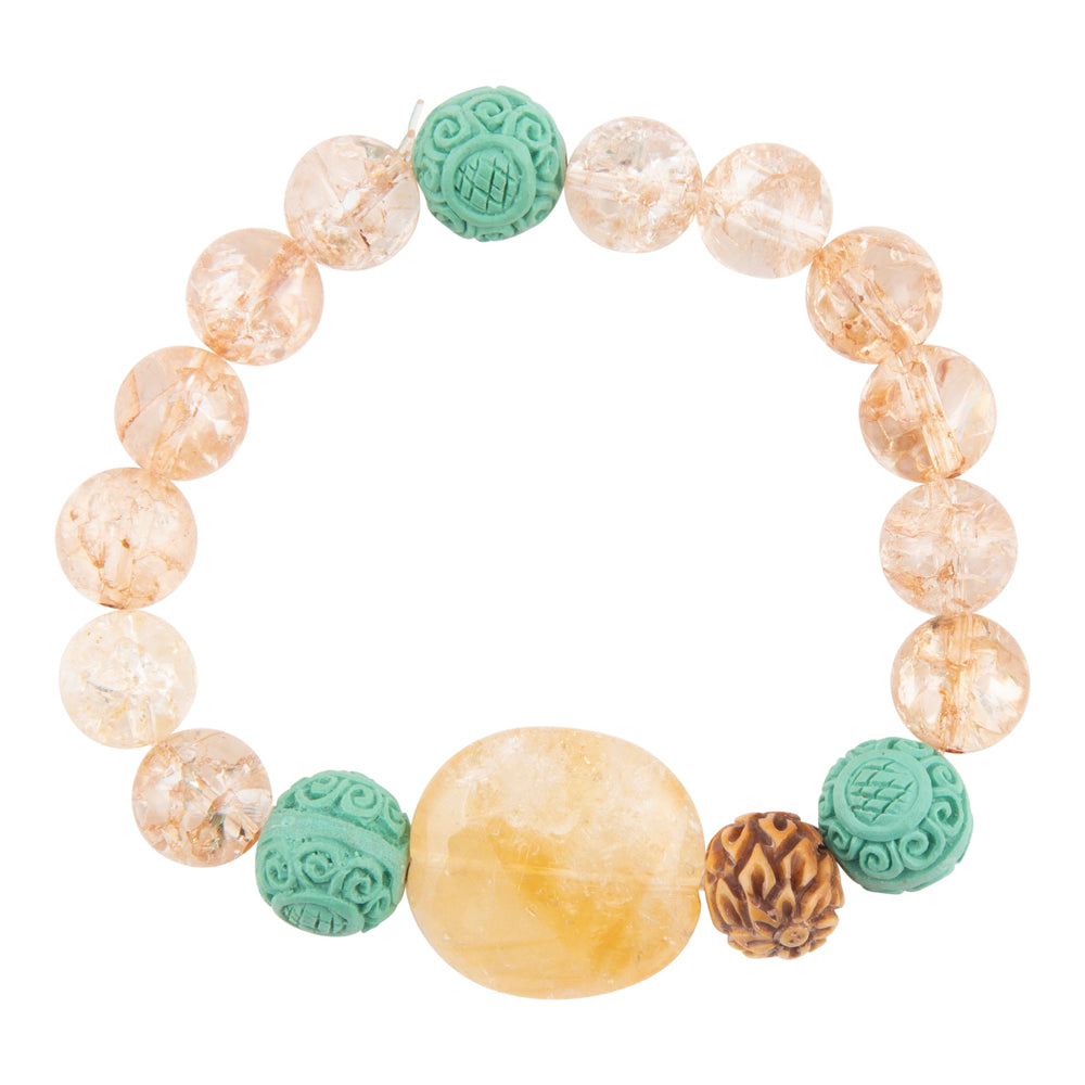 A beaded stretch bracelet featuring clear quartz crystal beads with internal inclusions, a large smooth yellow stone bead, and three carved turquoise-green accent beads, displayed on a solid white background.