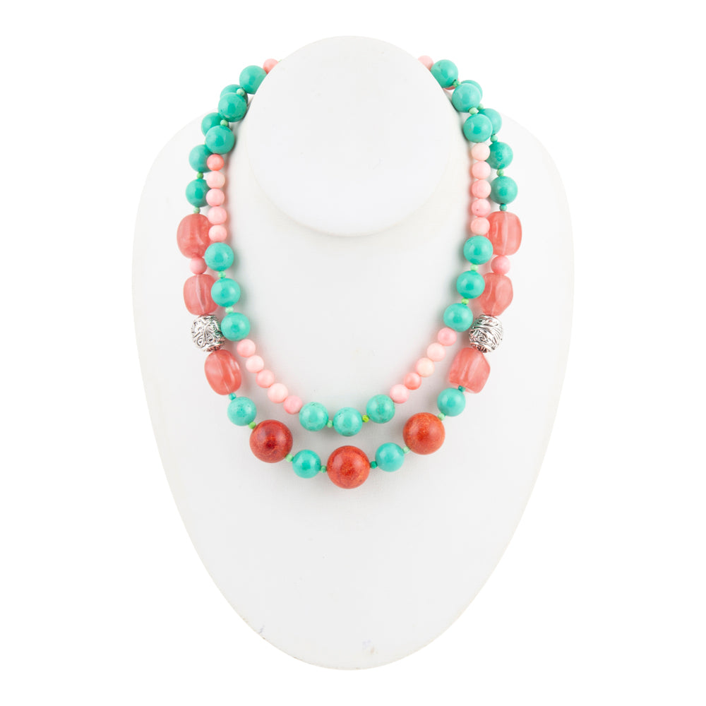 A double-strand beaded necklace displayed on a white mannequin bust. The necklace features turquoise beads, coral-red beads, and light pink beads, accented with two silver-toned spacer beads.