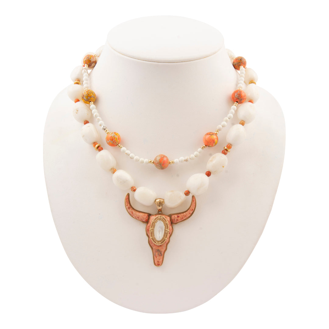 Necklace with white beads and a decorative pendant on a white stand