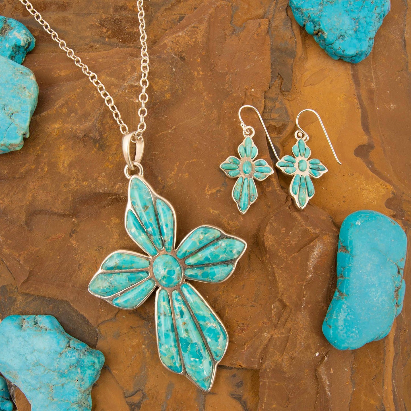 Turquoise butterfly necklace and earrings on a textured brown surface with turquoise stones.