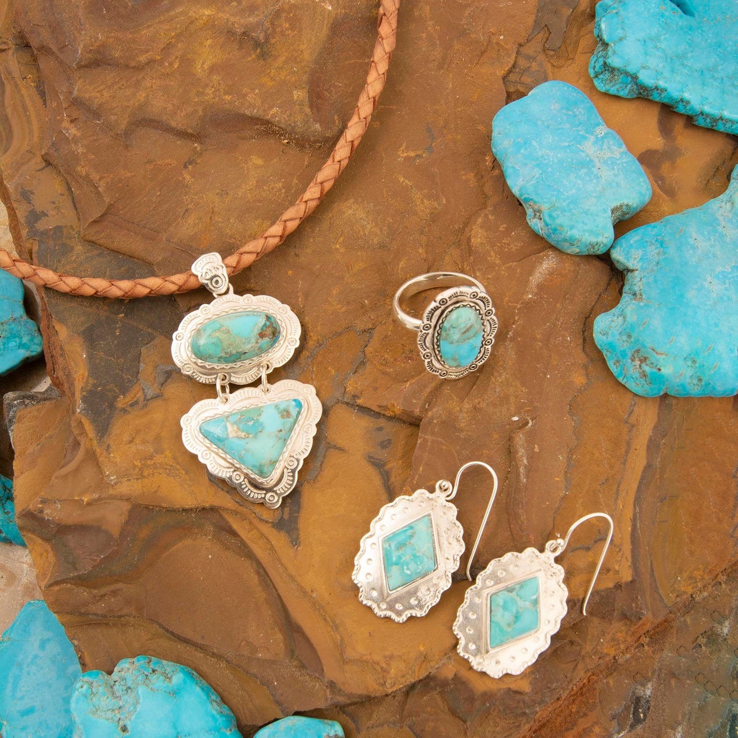 Turquoise jewelry set with necklace, ring, and earrings on a stone surface.
