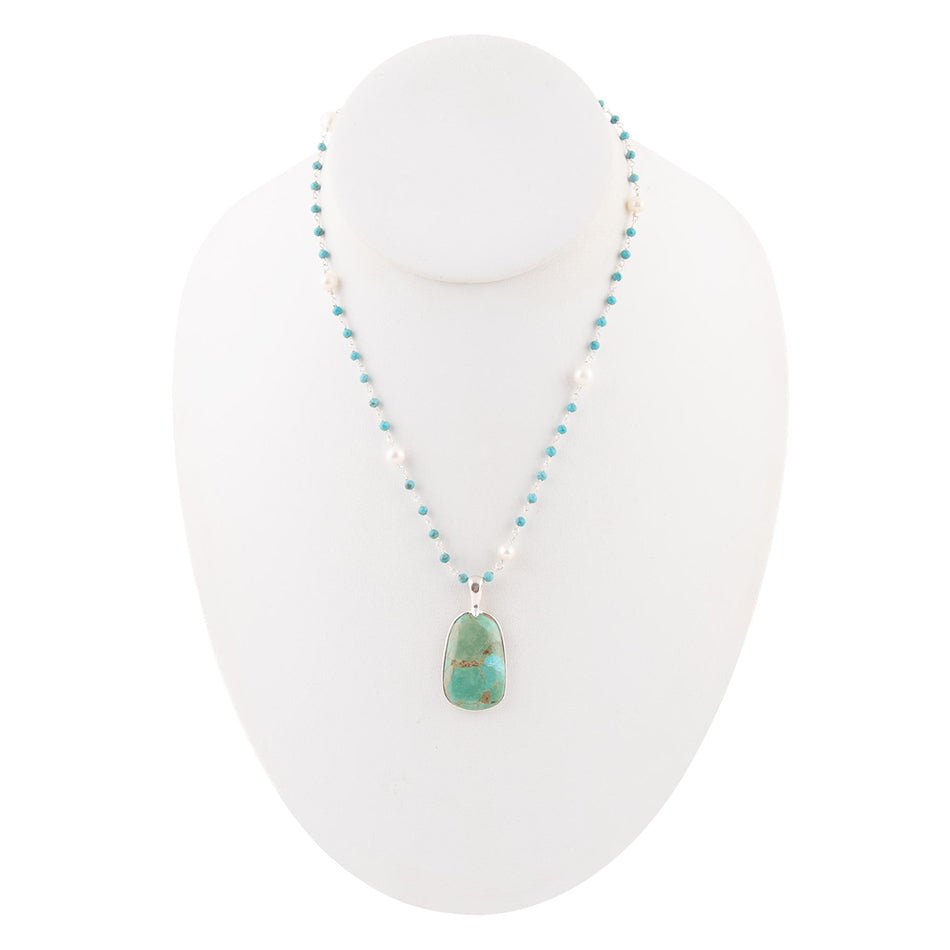 Necklace with turquoise pendant on a white stand