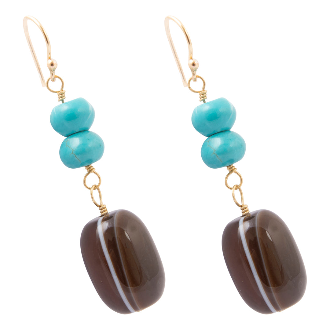 A pair of gold-tone dangle earrings featuring three stacked turquoise beads and a large, polished dark brown agate drop with a white band, set against a plain white background.