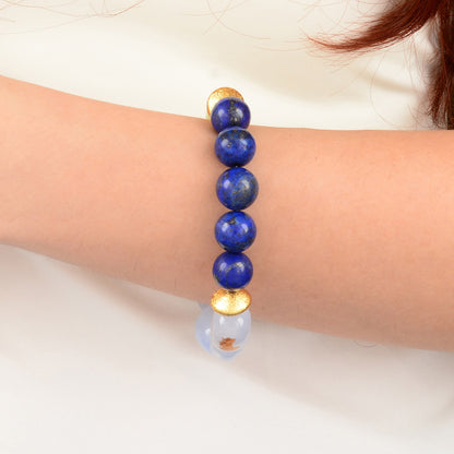 Bracelet with blue beads and gold accents on a wrist against a white background