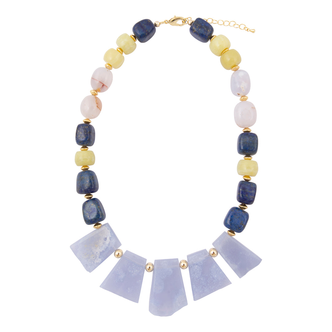 A statement necklace featuring a row of light lavender quartz crystal fans at the center, flanked by alternating dark blue lapis lazuli, pale yellow citrine, and white marble round beads, accented with small gold spacers and a gold clasp.