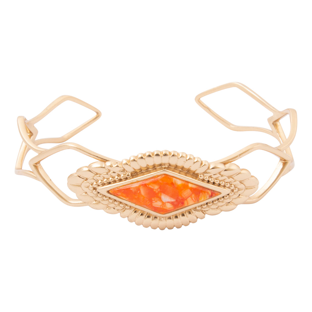 A gold-toned cuff bracelet featuring a central diamond-shaped orange opal inlay, set within a textured scalloped bezel and framed by openwork gold wire loops.