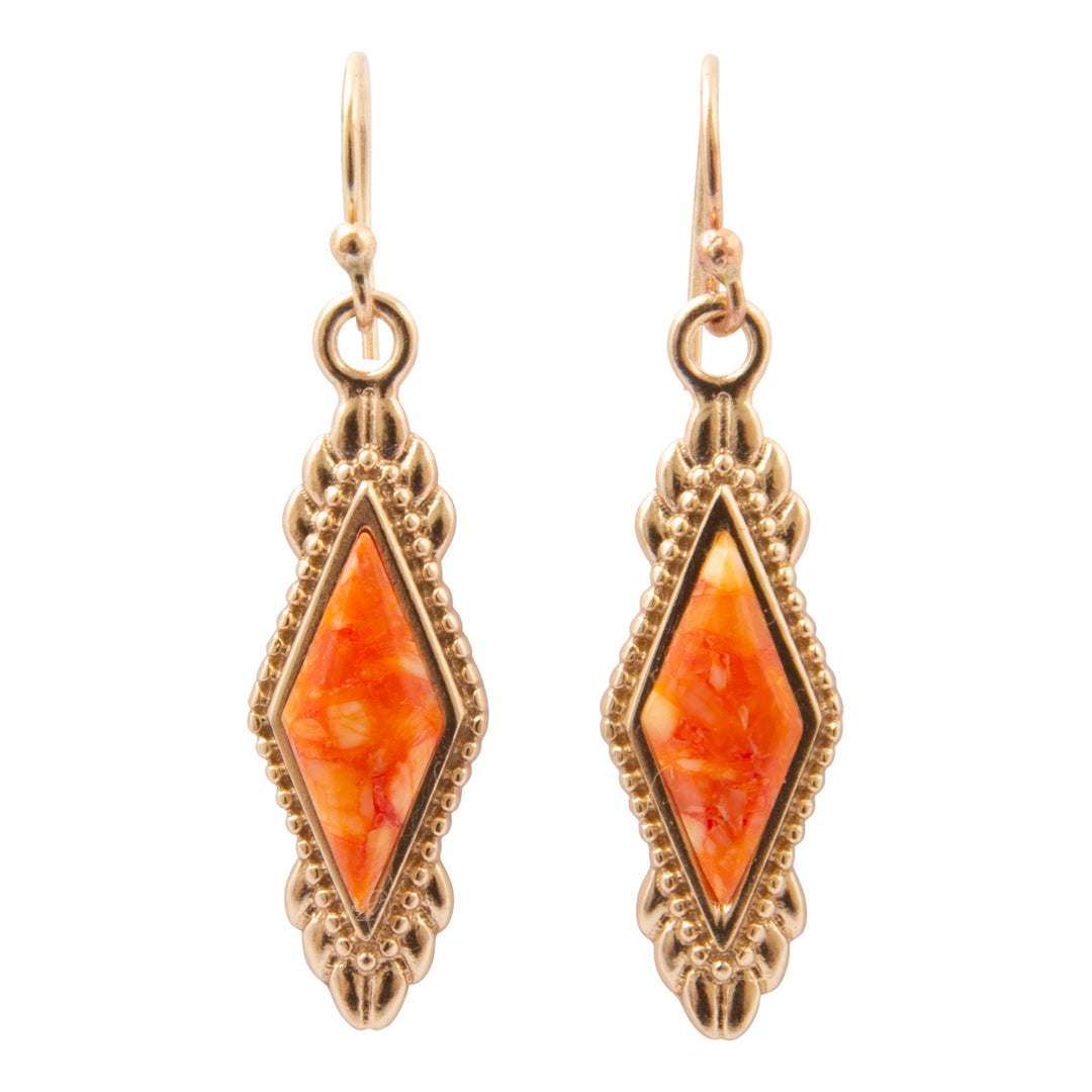 A pair of gold-toned drop earrings with ornate filigree borders and central diamond-shaped orange marbled inlay, shown on a plain white background.