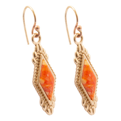 A pair of gold drop earrings featuring a marquise-shaped orange and yellow marbled stone inlay, set in ornate gold filigree frames with fishhook wires, shown on a plain white background.