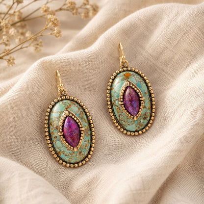 Pair of earrings with purple gemstones on a beige fabric background