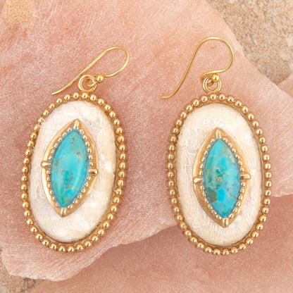 Pair of earrings with gold and turquoise stones on a stone surface