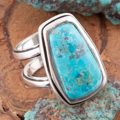 Turquoise ring with silver band on a natural stone background