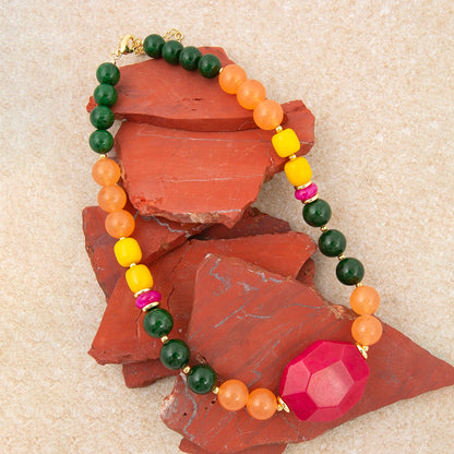 Colorful beaded bracelet with a large pink gemstone on a textured surface