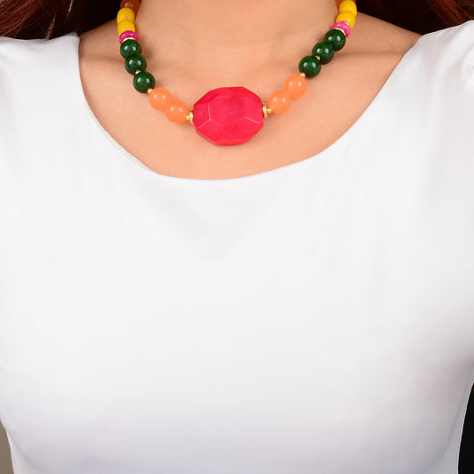 Colorful beaded necklace with a pink central bead worn by a person in a white shirt.