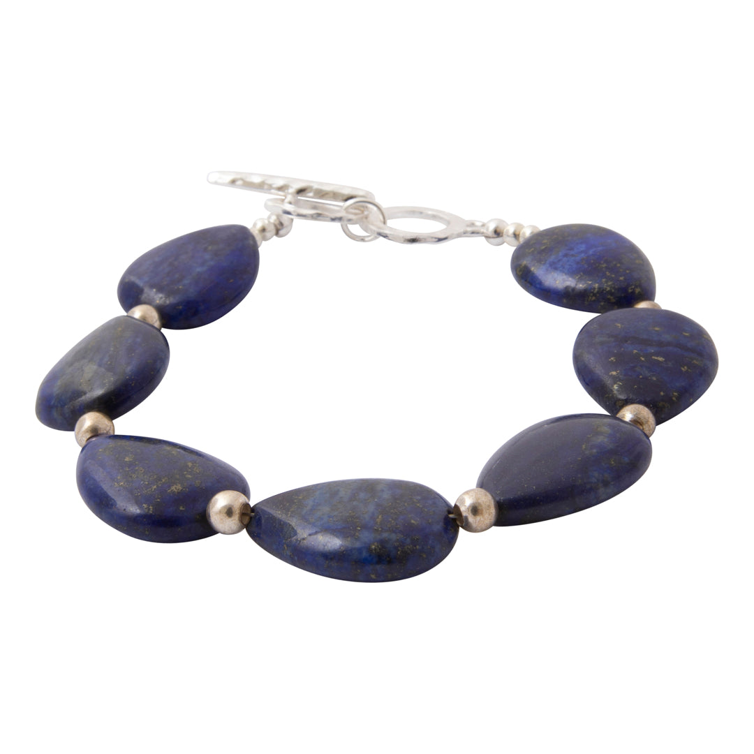 A beaded bracelet featuring polished dark blue lapis lazuli stones separated by small metallic spacer beads, finished with a silver toggle clasp, shown on a plain white background.