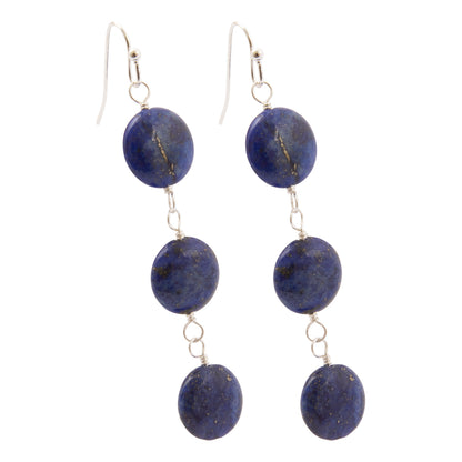 A pair of dangle earrings featuring oval lapis lazuli stones in deep blue with natural gold veining, suspended from silver-toned French hook ear wires on a plain white background.