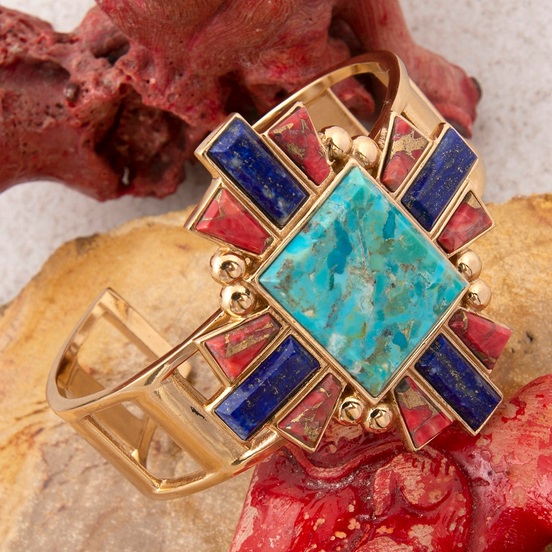 Gold bracelet with colorful gemstones on a natural stone background
