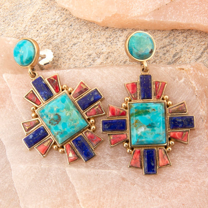 Colorful earrings with turquoise, red, and blue stones on a stone surface
