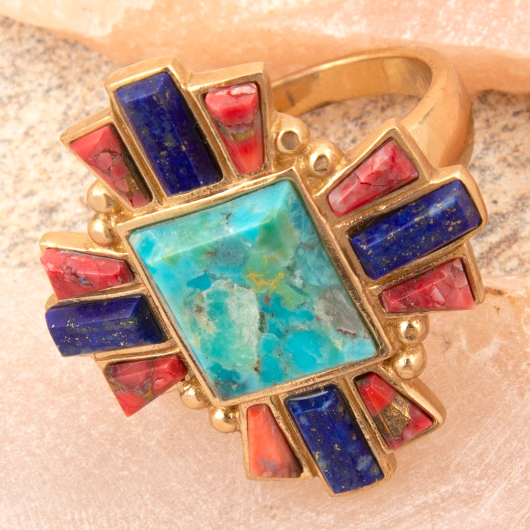 Gold ring with colorful gemstones on a textured surface