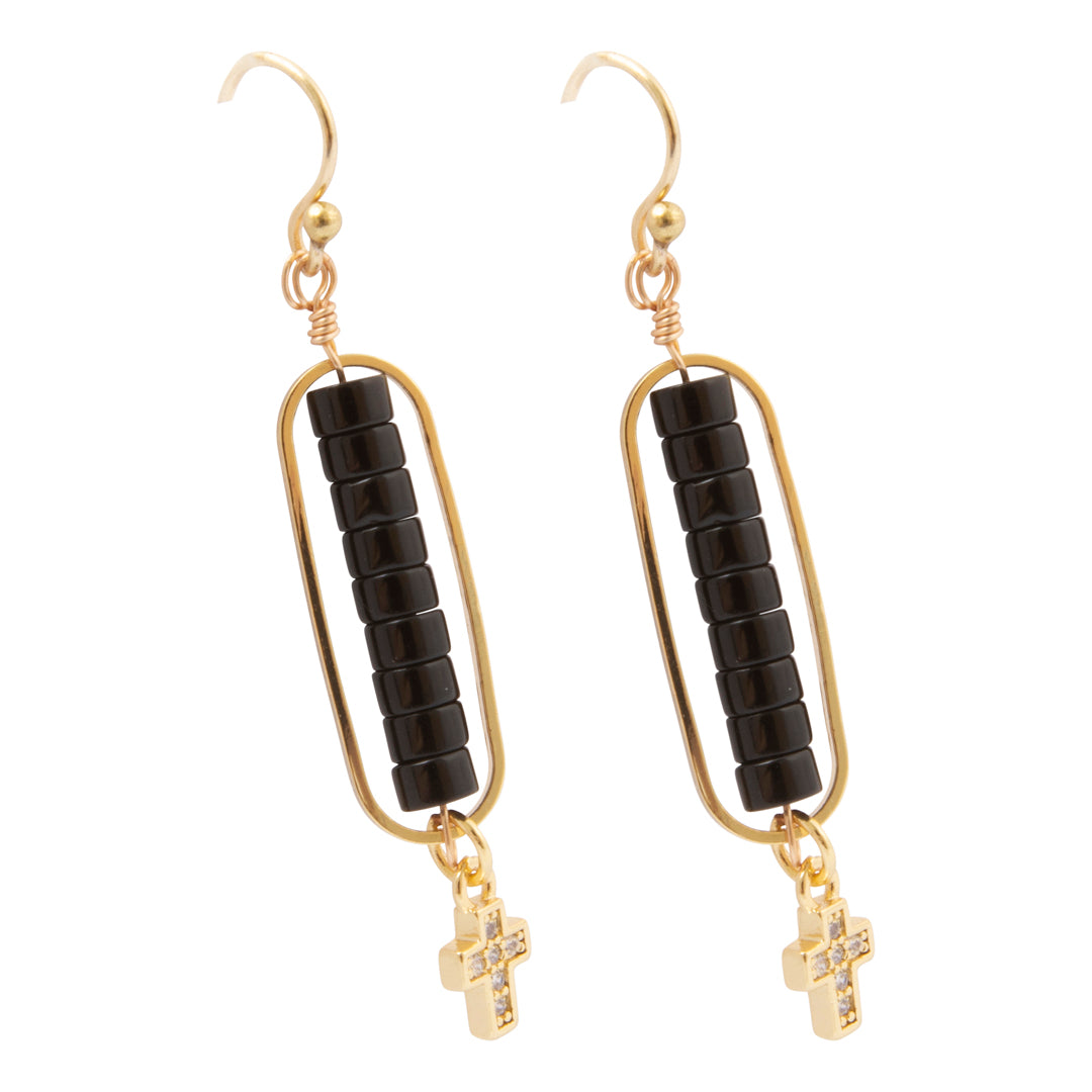 A pair of gold and black drop earrings with a textured rectangular frame, a central column of black beads, and a small gold cross charm dangling at the bottom.