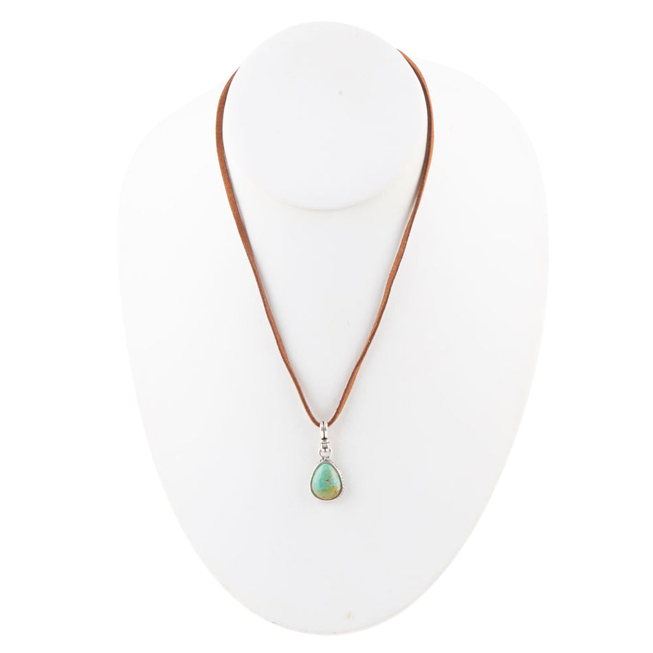 Necklace with a green teardrop pendant on a white stand