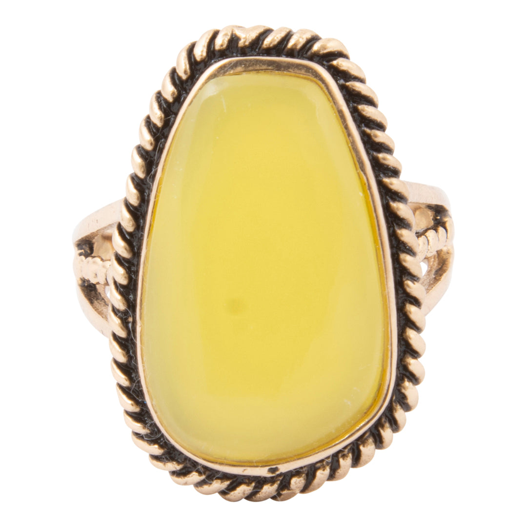 Ring with yellow stone and gold band on a white background
