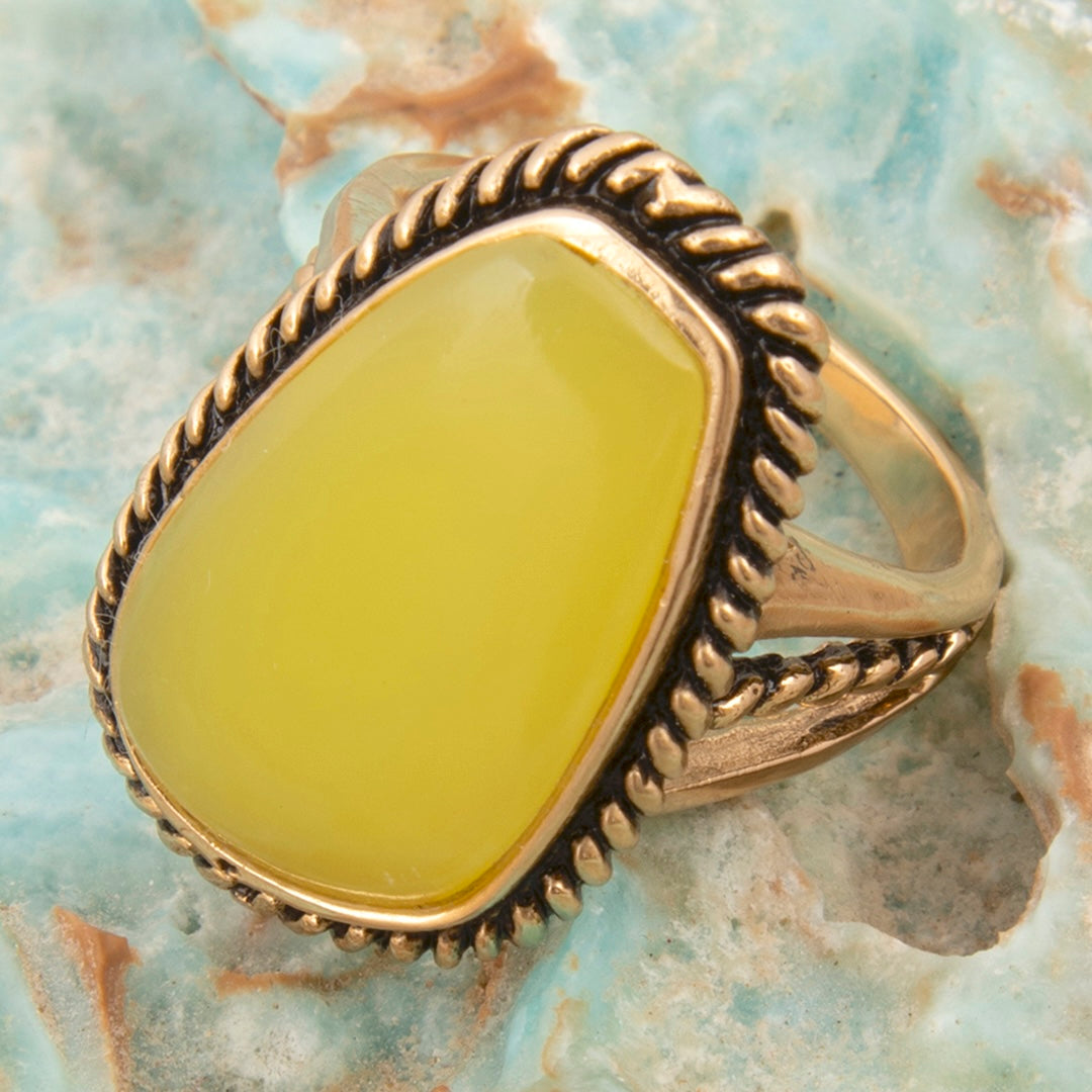 Gold ring with a yellow stone on a textured stone background