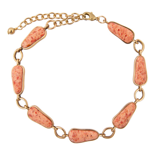 Gold bracelet with coral-colored stone links on a white background