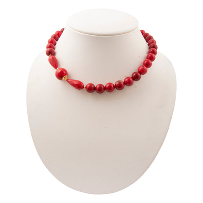 A red beaded necklace displayed on a white neck bust against a white background.