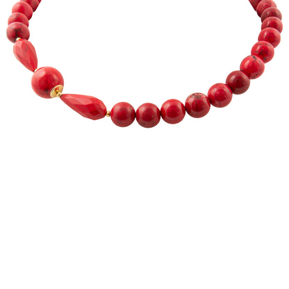 A red beaded necklace featuring a mix of smooth round beads, faceted teardrop beads, and a small gold spacer, shown against a plain white background.