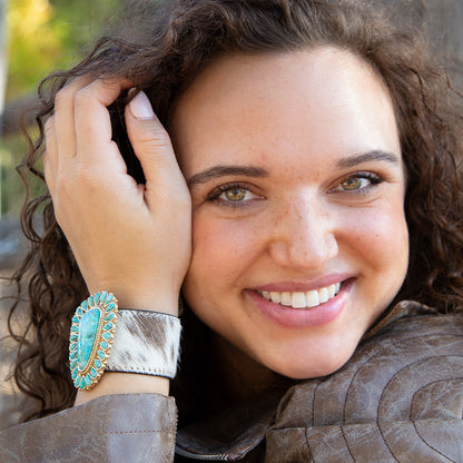 Woman wearing a turquoise bracelet and brown jacket outdoors