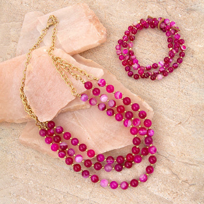Beaded necklace and bracelet set on a stone surface