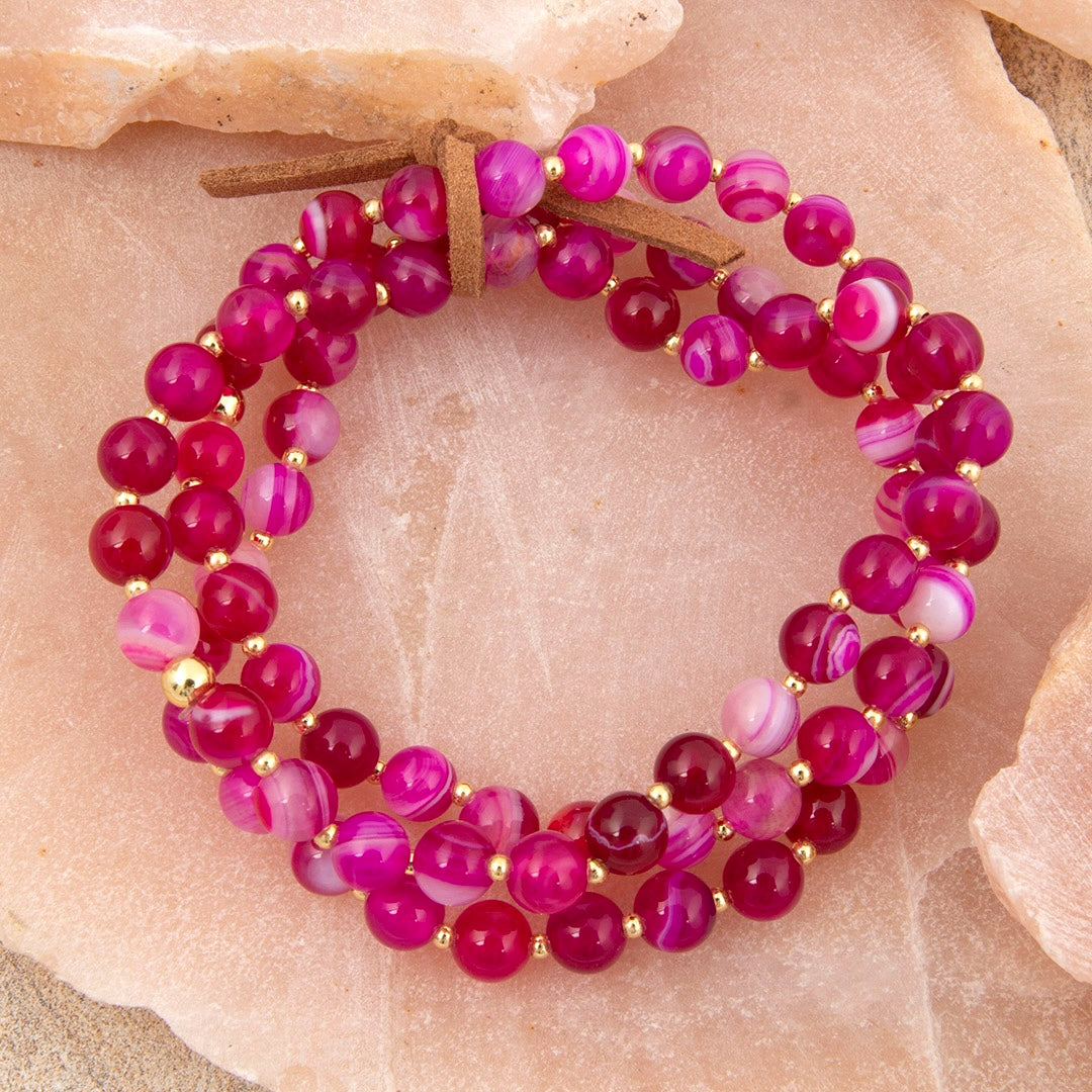 Multistrand bracelet with pink and purple beads on a stone surface