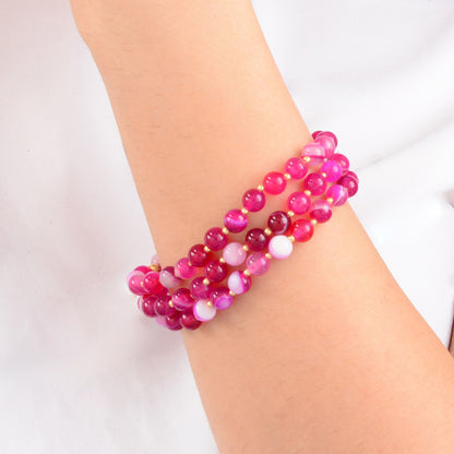 Pink beaded bracelet on a wrist against a white background