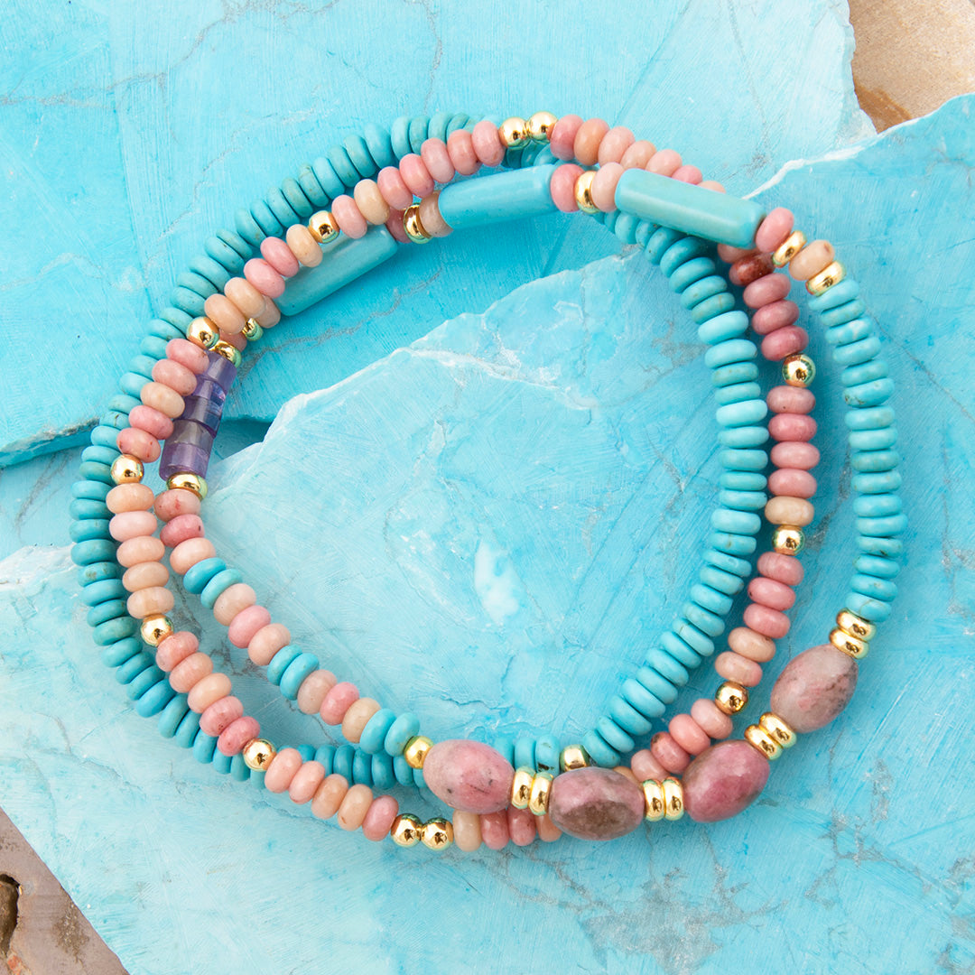 Set of colorful beaded bracelets on a light blue stone surface