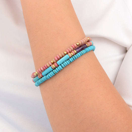Multicolored beaded bracelets on a wrist against a white background