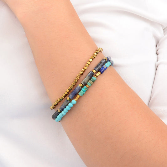 Three beaded bracelets on a wrist against a white background