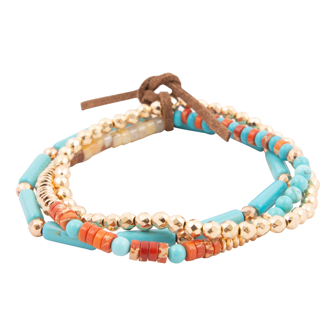 Multicolored beaded bracelet with brown leather strap on a white background