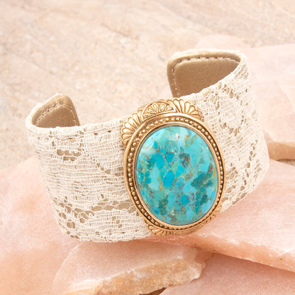 Bracelet with turquoise stone and gold detailing on a beige lace background
