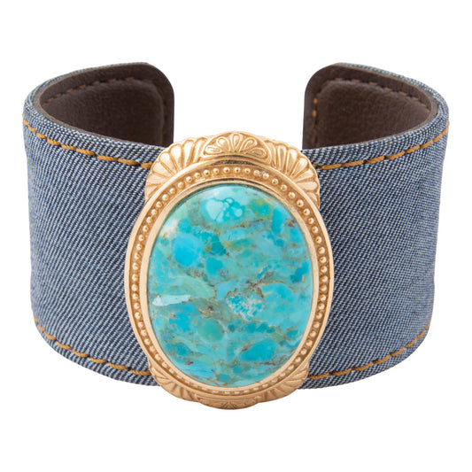 Denim cuff bracelet with a turquoise stone and gold frame on a white background