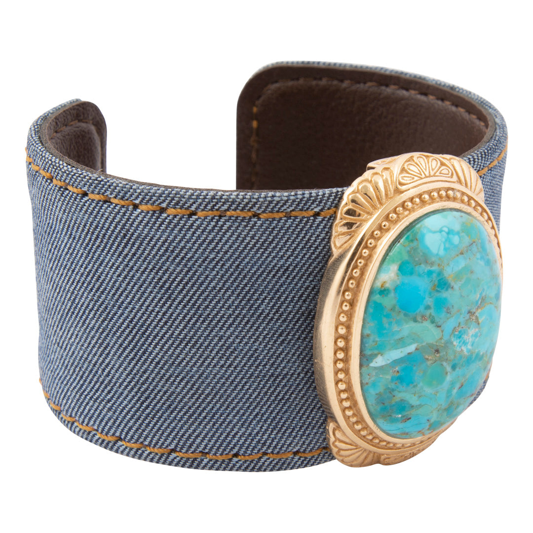 Denim cuff bracelet with a turquoise stone and gold accents on a white background