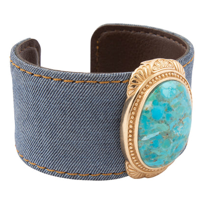 Denim cuff bracelet with a turquoise stone and gold accents on a white background
