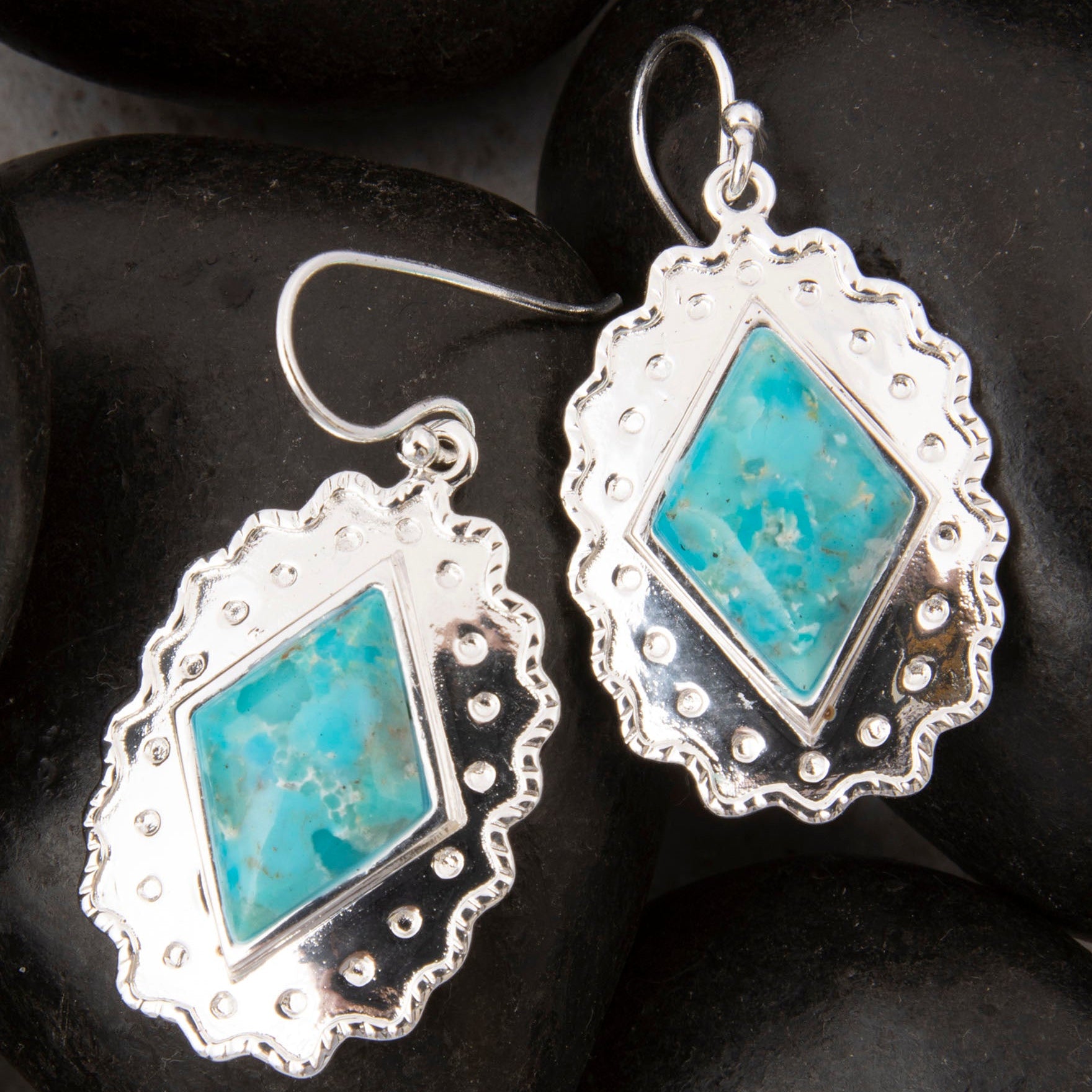Silver earrings with turquoise stones on a dark stone background