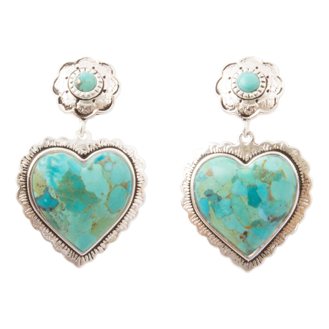 A pair of silver heart-shaped dangle earrings featuring turquoise stones with brown matrix, set in a floral stud design on a plain white background.