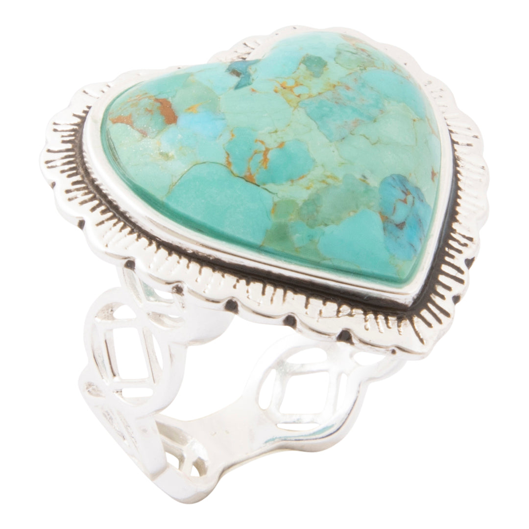 A sterling silver ring featuring a large, scalloped heart-shaped turquoise cabochon with natural brown and gold matrix veining, set on a decorative openwork band.