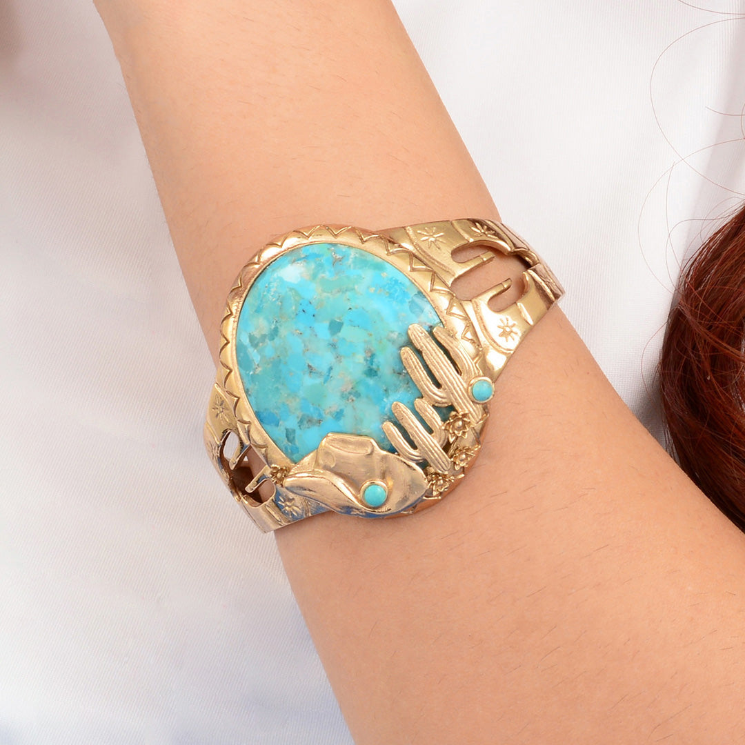 Gold bracelet with turquoise stone on a wrist against a white background