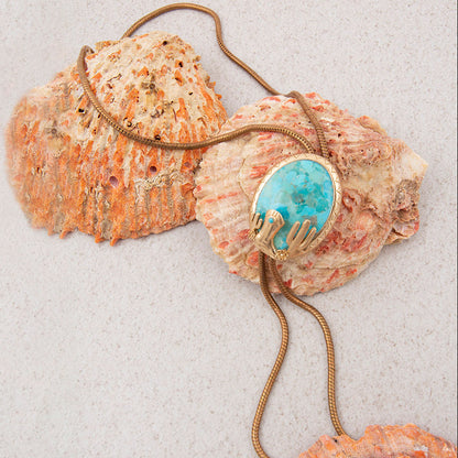 Jewelry with a turquoise stone and gold accents on seashells.
